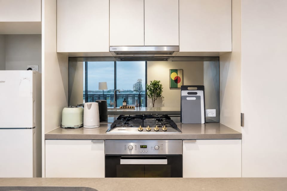 Modern kitchen with gas cooktop, sleek finishes, and city-view reflections