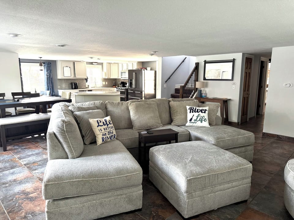 Spacious open living room with oversized sectional, dining area, and full kitchen