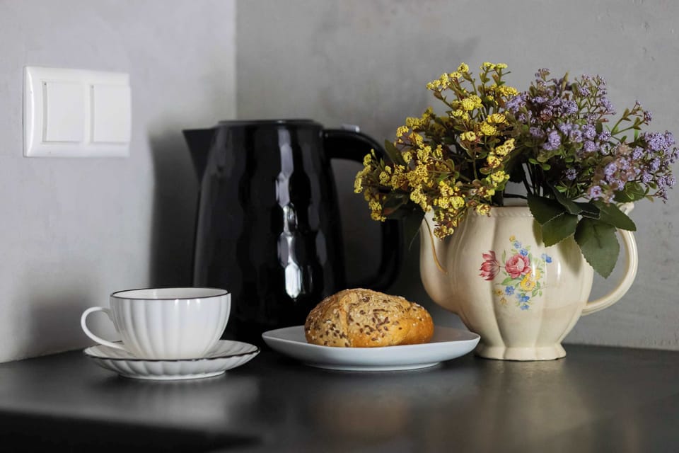 Decorative kitchen countertop with coffee cups, pastries, flowers, and elegant tableware.