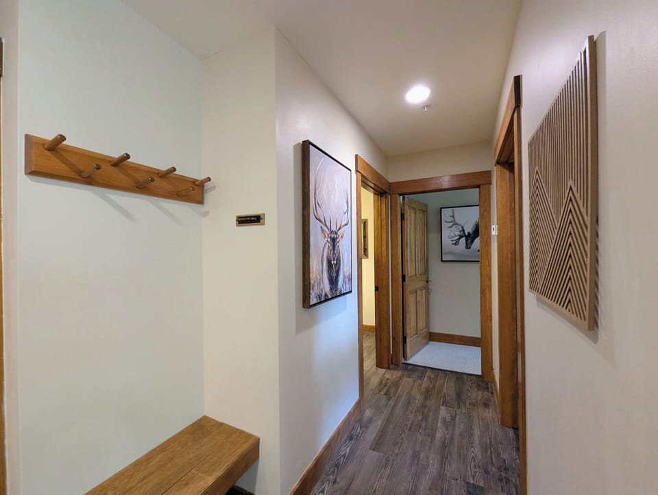 A welcoming entry hallway with warm wood accents, thoughtful coat hooks, and tasteful wildlife art sets a cozy, mountain-inspired tone the moment you arrive.