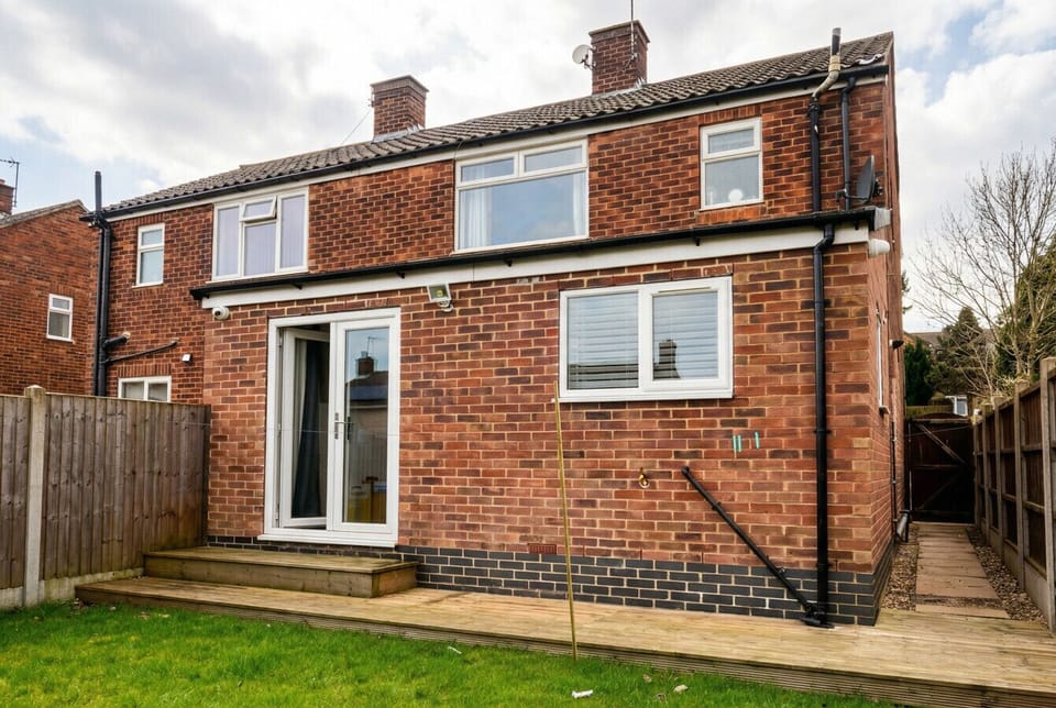 The rear of the home shows the new timber decking and French doors leading to a private garden.