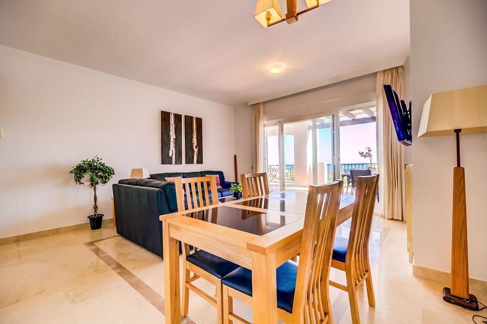 Bright dining and lounge area with balcony access and partial sea views