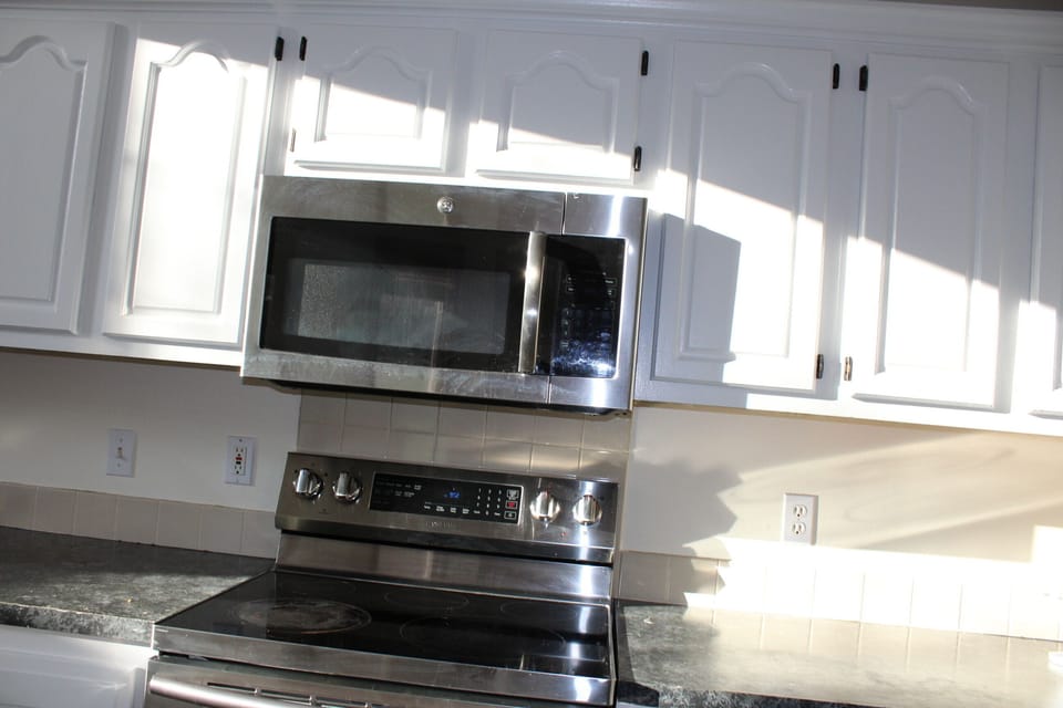 Sunny kitchen with stainless appliances, white cabinets, roomy counters.