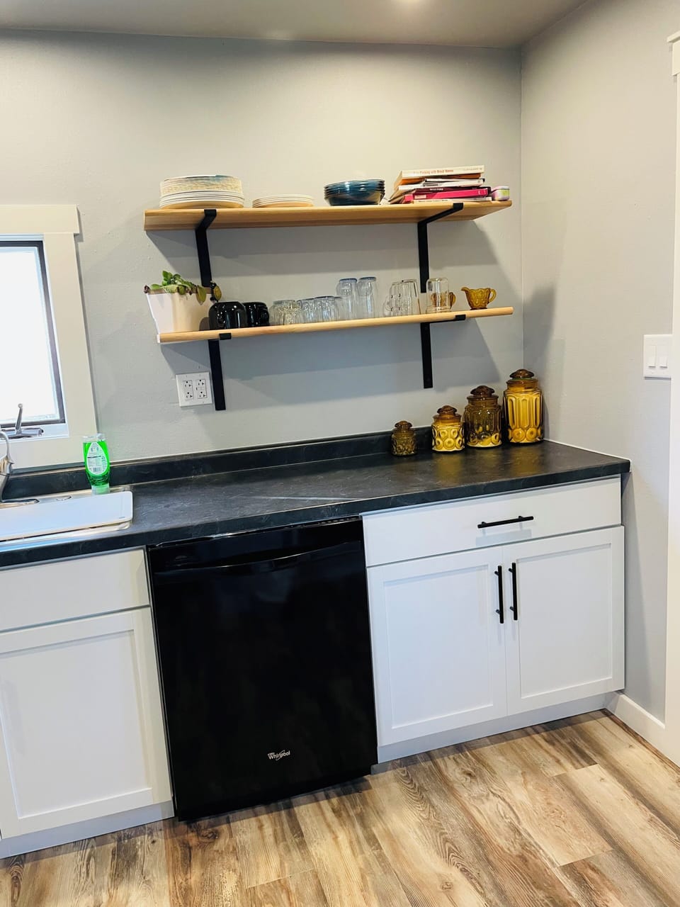 Modern kitchenette with open shelving, mini fridge, and sleek finishes