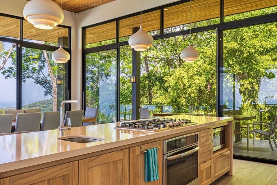 Spacious chef’s kitchen and dining area designed for gathering, featuring a large live-edge dining table, premium appliances and seamless indoor-outdoor living.