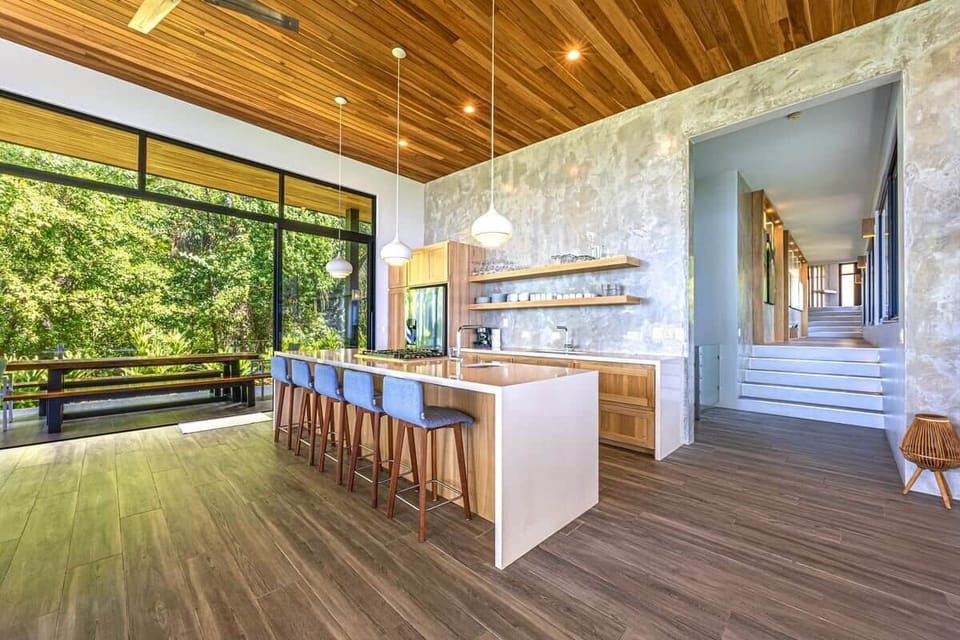 Spacious chef’s kitchen and dining area designed for gathering, featuring a large live-edge dining table, premium appliances, bar seating, and seamless indoor-outdoor living.