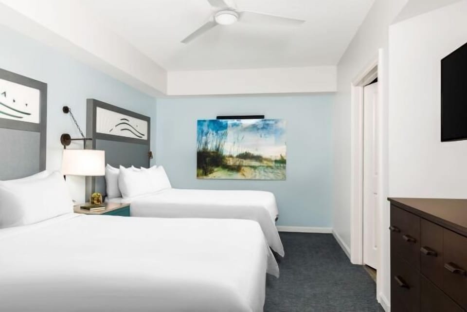 Bright double-bed room with TV, dresser, and a calm coastal feel