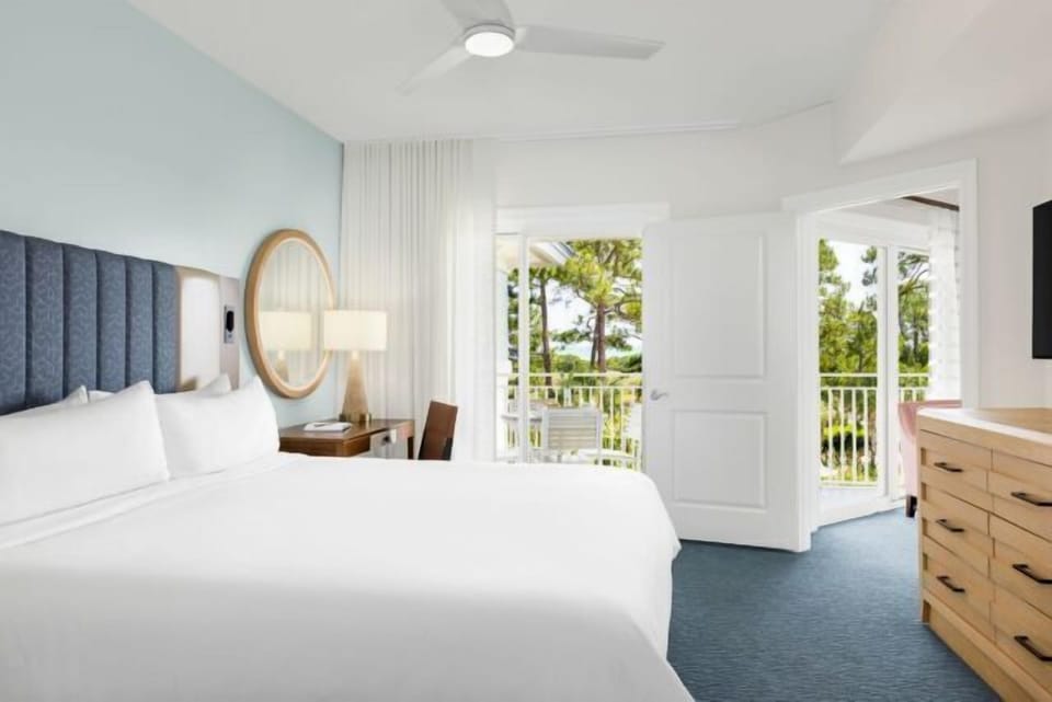 Bright coastal bedroom with private balcony and peaceful treetop views