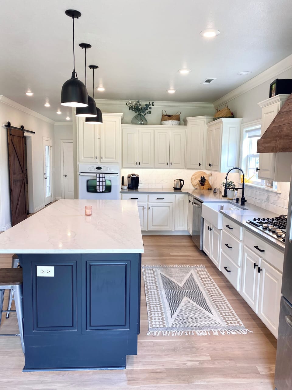 5 burner gas cooktop, double ovens, farmhouse sink, and under-cabinet lighting.