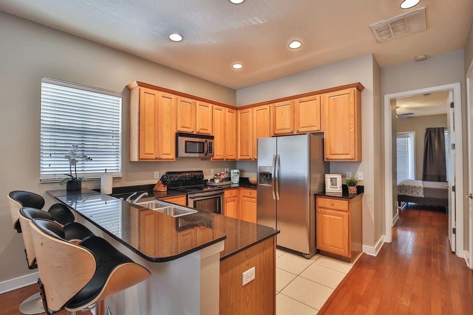 Full kitchen with granite breakfast bar, stainless-steel appliances, and seating for four.