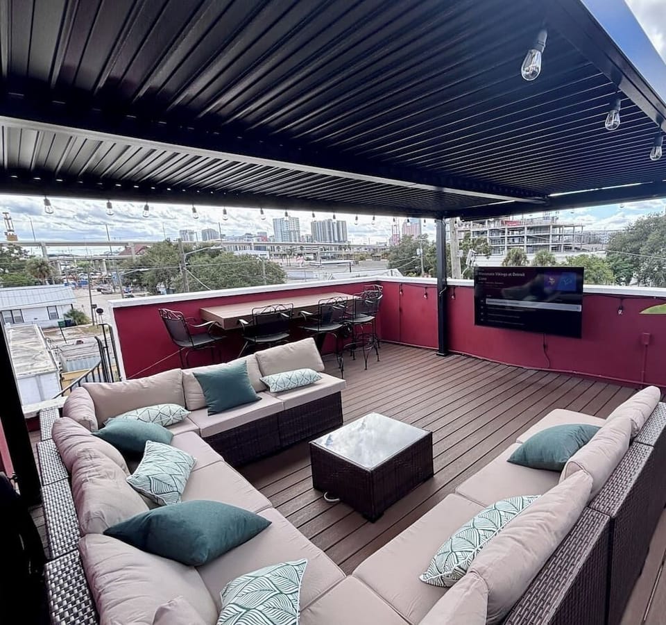 Private rooftop terrace with shaded cabana, sectional seating, outdoor TV, bar, and Tampa skyline views.