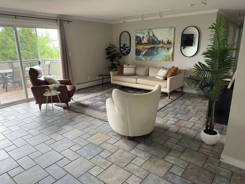 Relax in this bright and stylish living room, featuring comfortable seating, modern décor, and direct access to the outdoor deck.