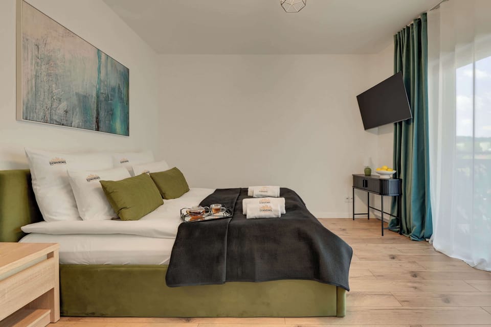 Przestrzeń apartamentu łączy funkcję sypialni, części wypoczynkowej i jadalnianej. Znajduje się w niej wygodne łóżko małżeńskie z hotelową pościelą i kompletem poduszek oraz rozkładana sofa zapewniająca dodatkowe miejsce do spania dla jednej osoby. 