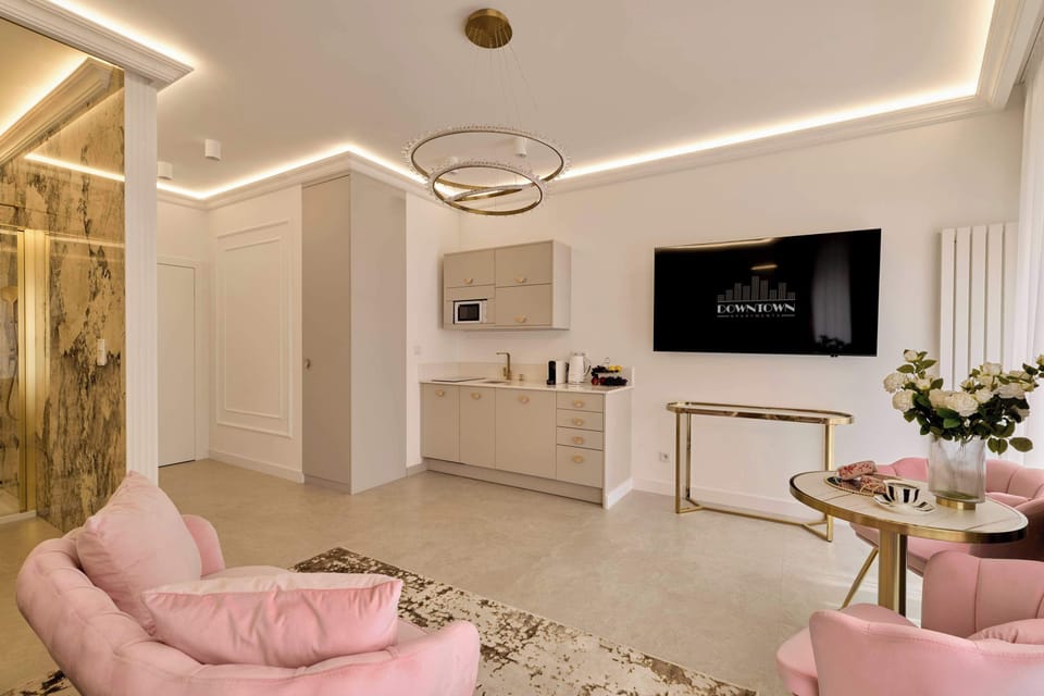 Przestrzeń apartamentu łączy funkcję sypialni, części wypoczynkowej i jadalnianej. Znajduje się w niej wygodne łóżko małżeńskie przygotowane z hotelową pościelą i kompletem poduszek, niewielka sofa, fotele oraz telewizor Smart TV z kanałami kablowymi