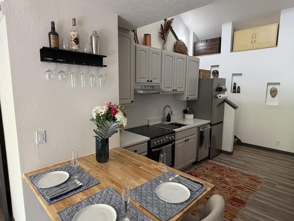 Cozy dining nook by kitchen with stairs leading to loft & workspace.