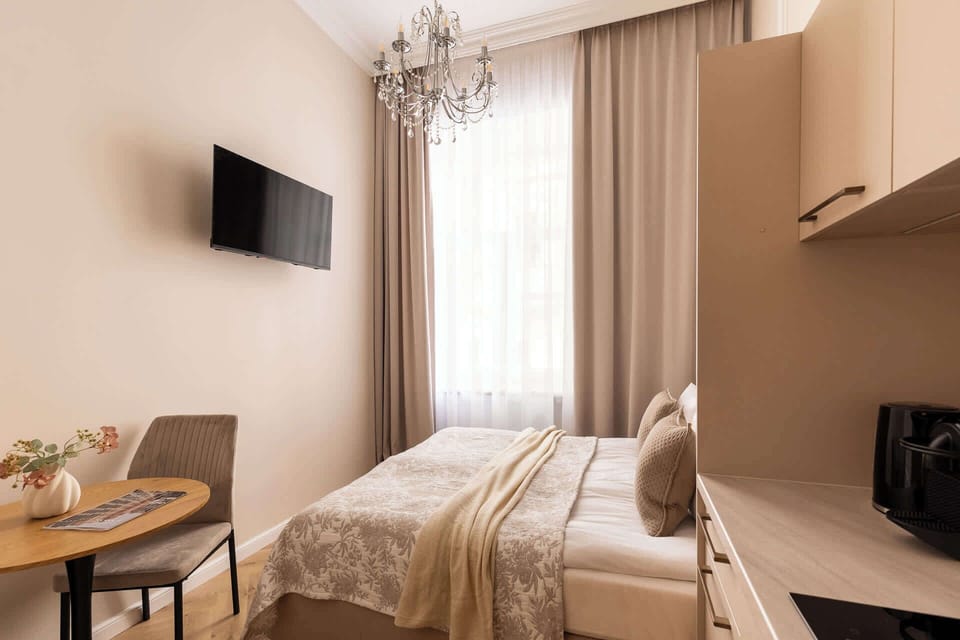 Przestrzeń apartamentu łączy funkcję sypialni i części wypoczynkowej. Znajduje się w niej wygodne łóżko małżeńskie z hotelową pościelą i kompletem poduszek oraz telewizor Smart TV z dostępem do kanałów satelitarnych.