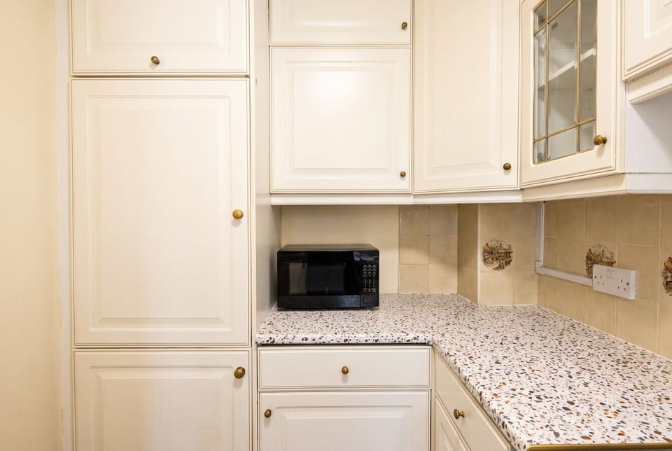 Cream kitchen with terrazzo counters and microwave for quick bites
