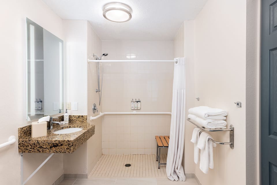 Accessible bathroom with roll-in shower and grab bars.