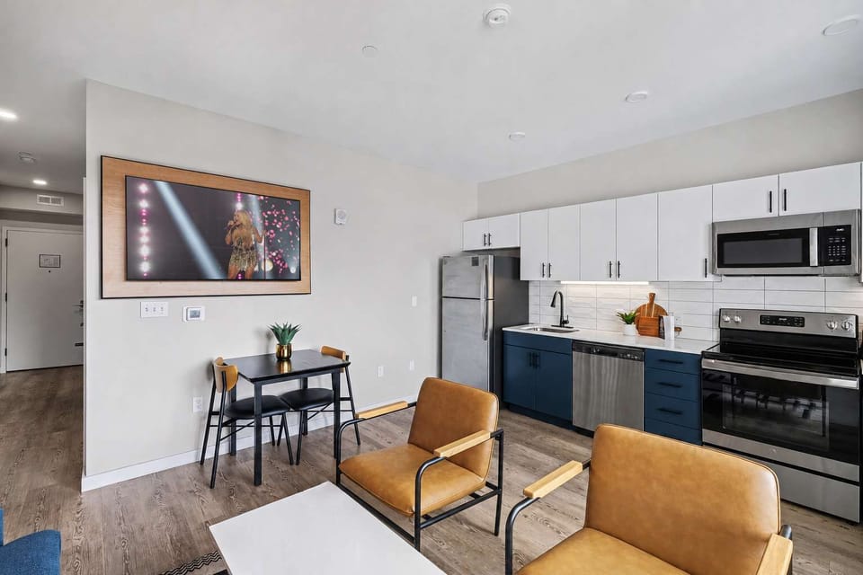 Bright, modern open-concept living with stylish seating, a fully equipped kitchen, and oversized windows framing the city view.