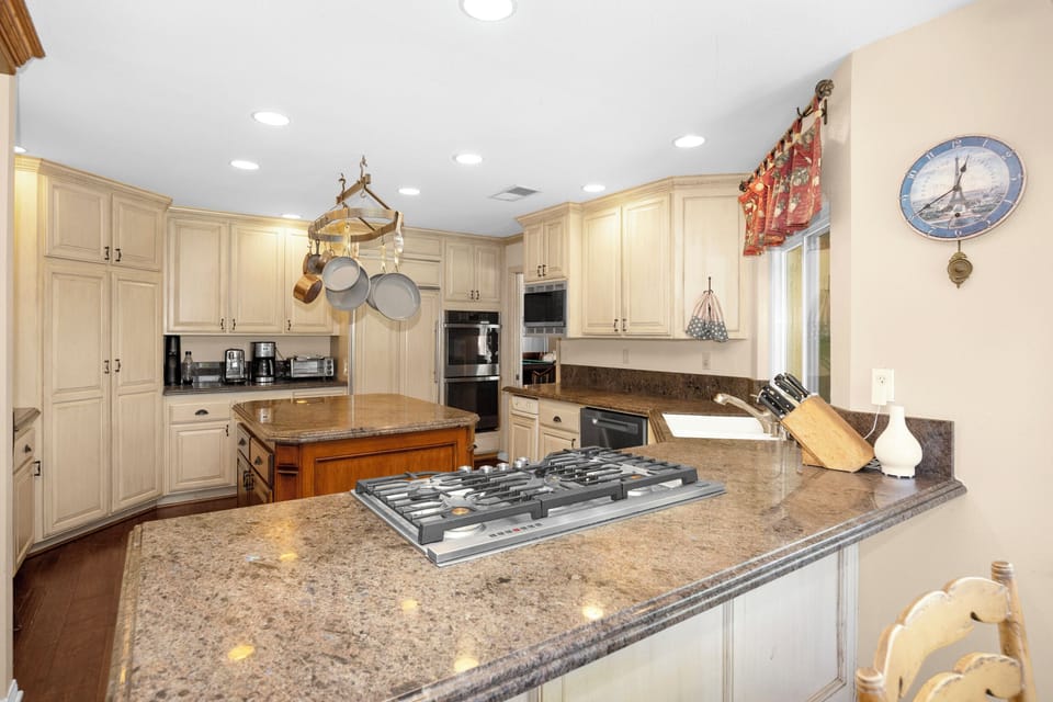 Spacious gourmet kitchen featuring a professional gas cooktop, double ovens, oversized island, and abundant prep space.