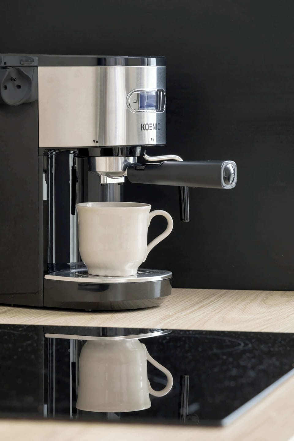 A close-up shot of an espresso machine pouring fresh coffee into a white cup. The metallic finish and sleek black background add a modern touch.
