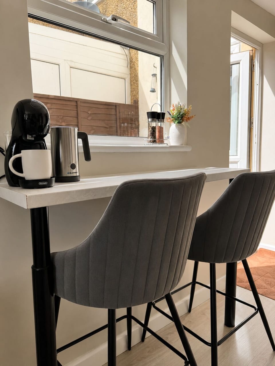 Contemporary sleek kitchen featuring a breakfast bar for two, coffee machine with milk frother, microwave, toaster, kettle, and more!