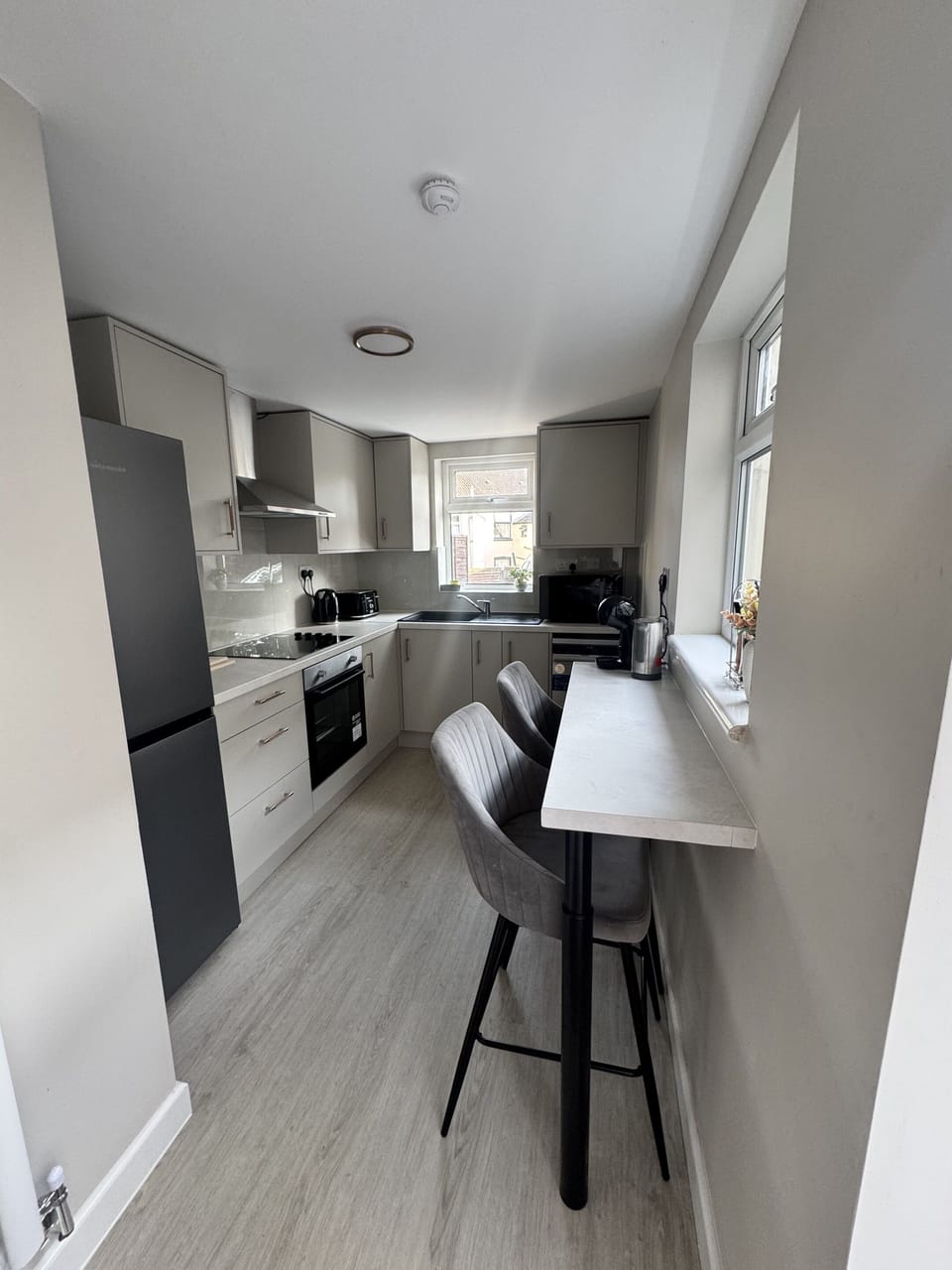Contemporary sleek kitchen featuring a breakfast bar for two, coffee machine with milk frother, microwave, toaster, kettle, and more!