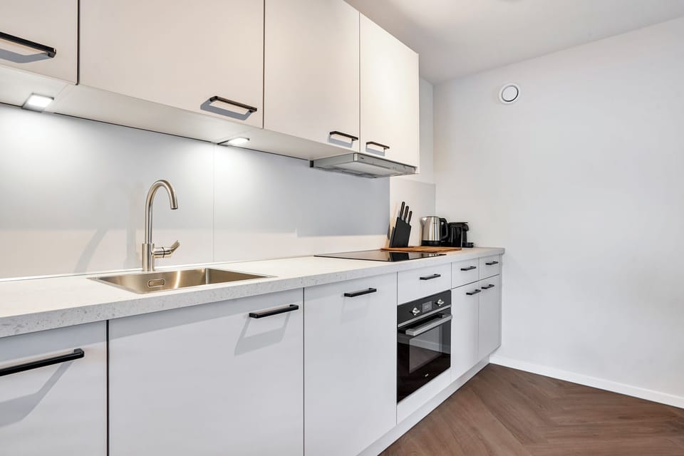 Modern private kitchen with an oven, cooktop, refrigerator, coffee maker, kettle, and everything needed to prepare meals.