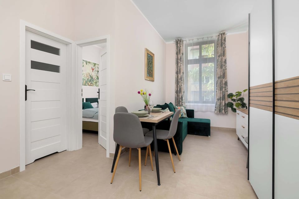 A dining area with a table and chairs by the window. An air conditioner is mounted on the wall.