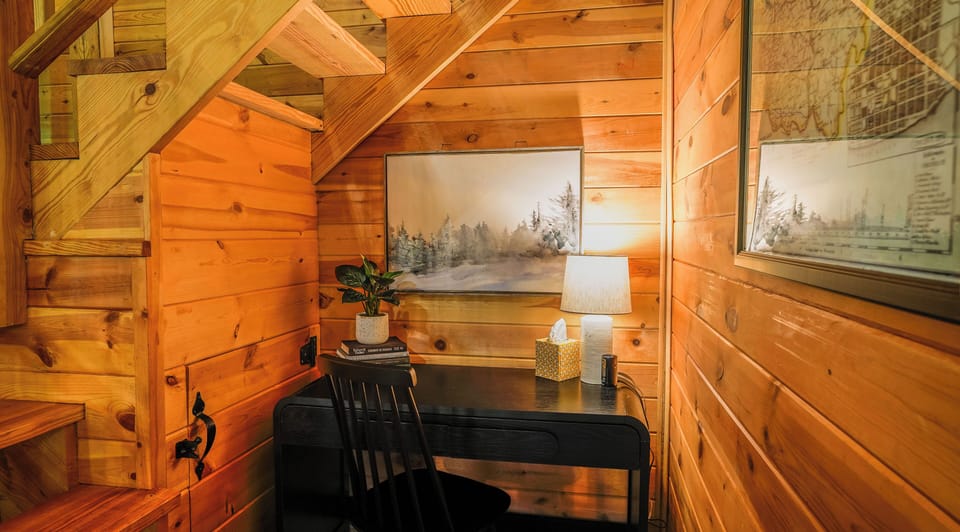 Warm lamp, winter landscape print, a small plant, books, and an Ohio trail map framed beside you. It's just cozy enough to make email feel almost pleasant. Almost.  