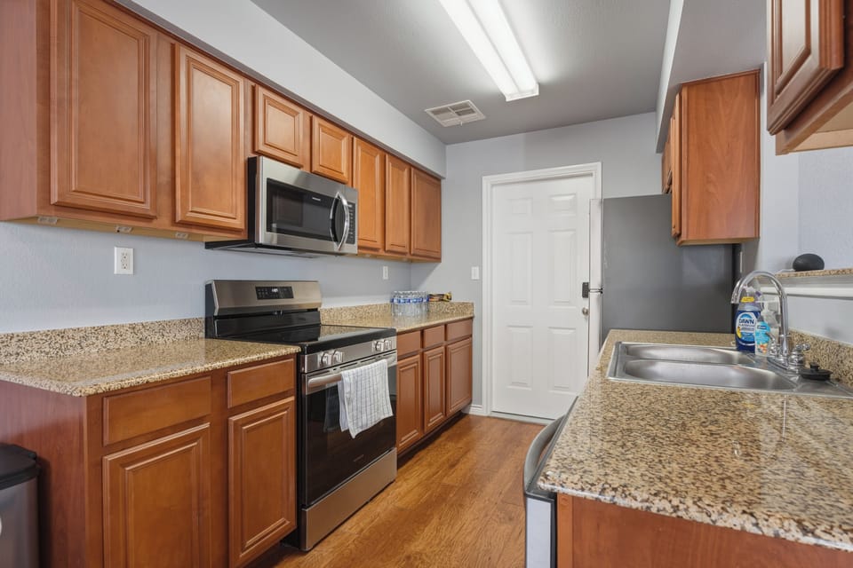 Stylish galley kitchen with granite, gas range, and ample storage