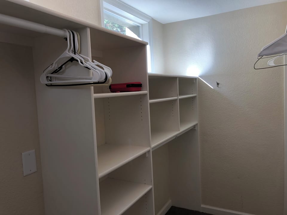 Primary walkin closet with hanging rods and shelving