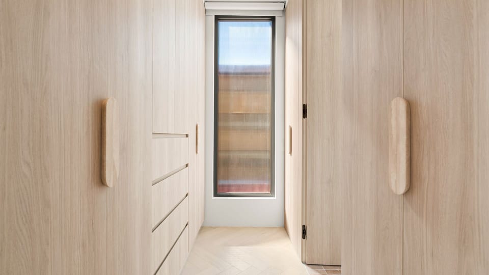 Light-filled hallway framed by custom cabinetry and a feature entry door.