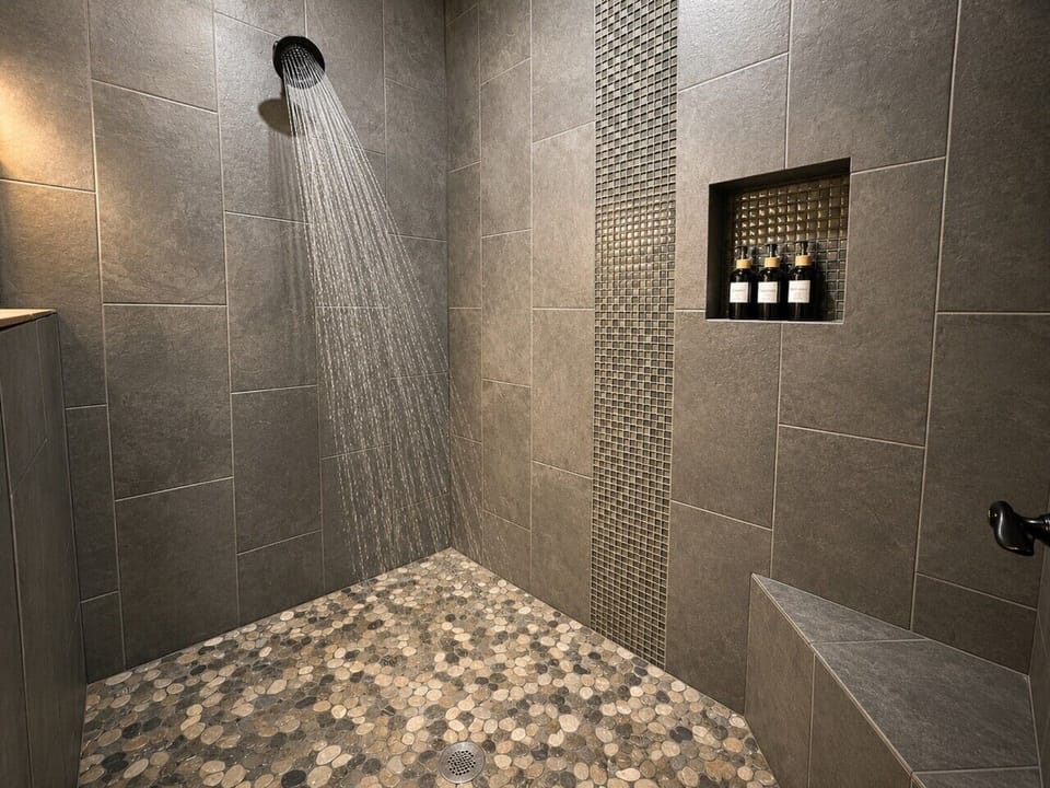 Walk-in rainfall shower with pebble floor and modern tile accents