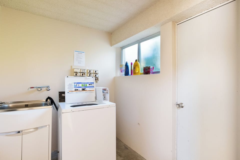 Bright on-site laundry room with washer, utility sink, and natural light