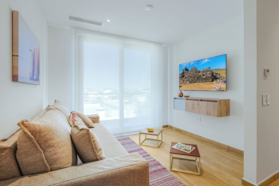 Relax on the plush sofa and enjoy your favorite shows in this light-filled living area, where floor-to-ceiling windows create a bright and airy atmosphere.