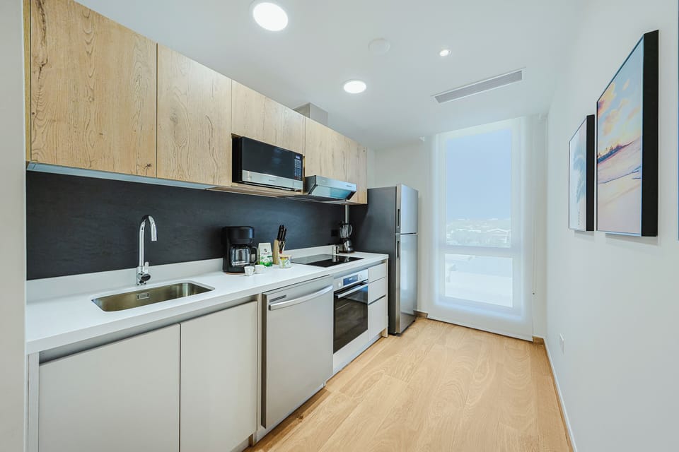 Your sleek modern kitchen features white countertops, stainless steel appliances, and natural wood accents—everything you need to prepare a quick snack or full meal during your stay.