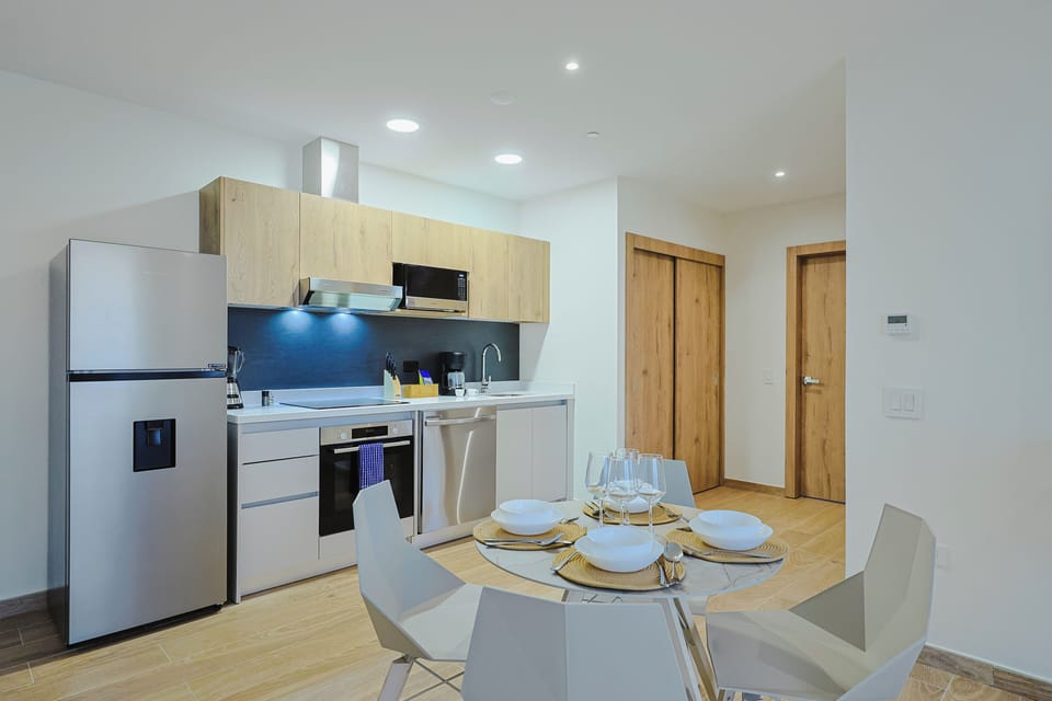 Step into your modern kitchen and dining space, where light wood accents meet sleek white finishes. Cook your favorite meals with full appliances, then gather around the table for a cozy breakfast or evening meal together.