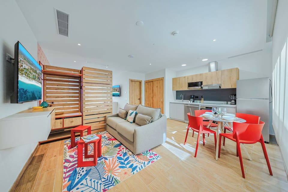 Your bright, modern retreat features an open living space with vibrant red accents, cozy seating, and a fully equipped kitchen ready for your home-cooked meals.