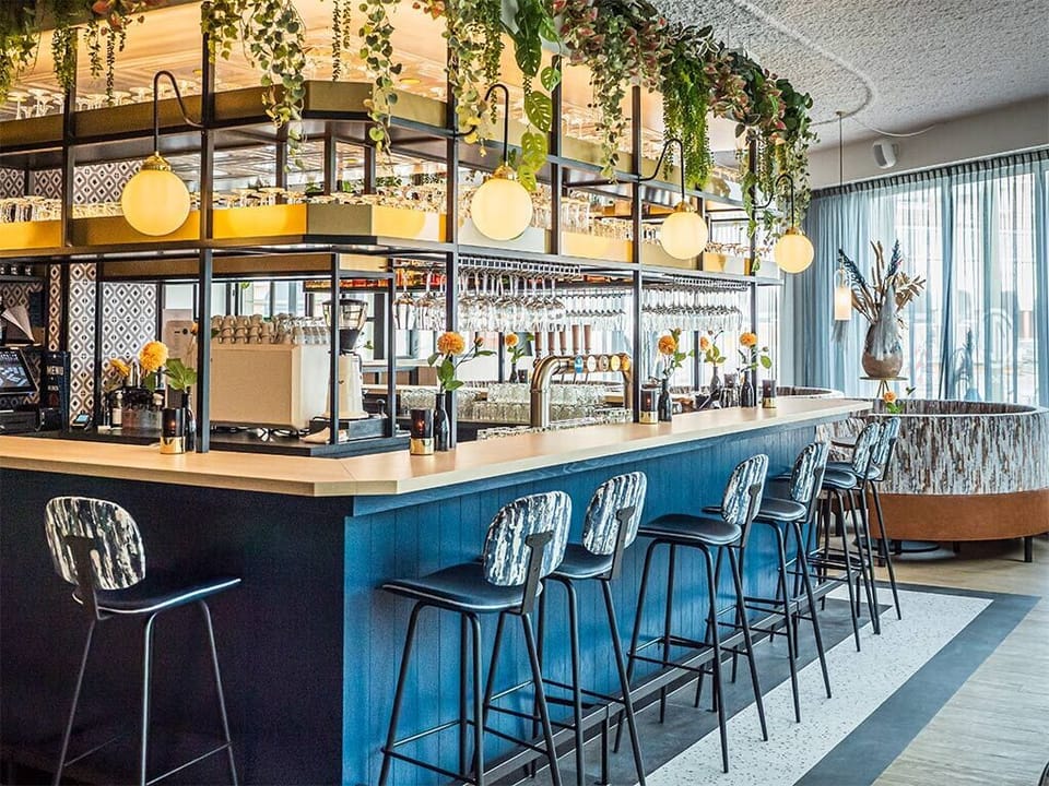 Sip crafted cocktails beneath warm lights and lush greenery.