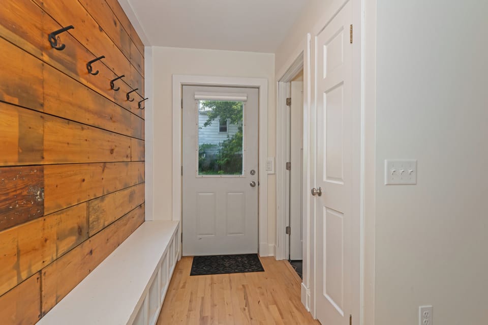 Rear entry with coat hooks and a bench for boots, bags, and gear.