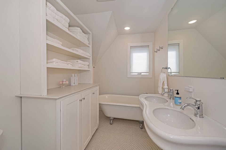 Upstairs bathroom with clawfoot soaking tub and double vanity.