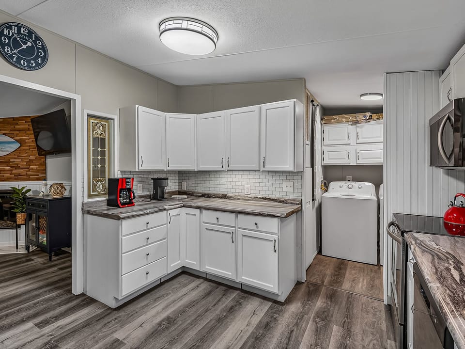 White cabinetry lines the kitchen, with a full-size fridge and stove for meal prep.