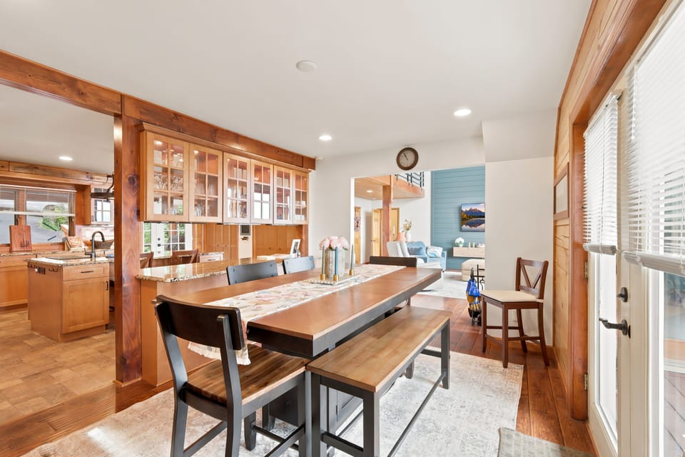 Stylish chairs pull up to the dining table in this bright, open space, where warm wood tones on the floor and walls keep things feeling like a real mountain home. Plenty of natural light makes it an easy spot for morning coffee or a long dinner here.