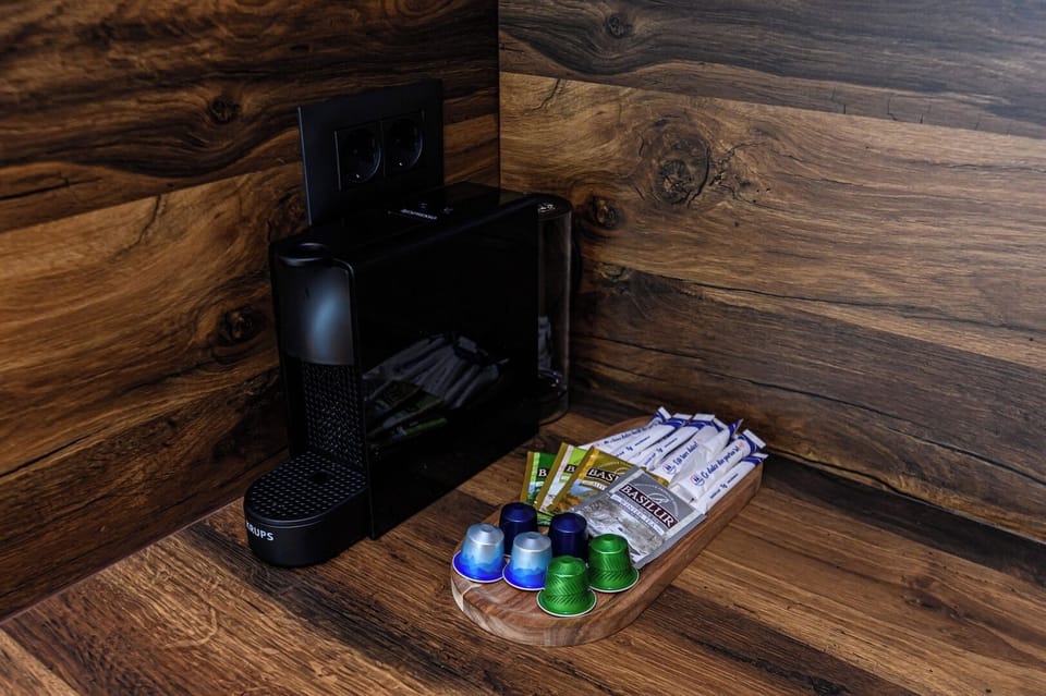Nespresso espresso machine with a selection of capsules provided on arrival. Set against the walnut wood backsplash panel in the kitchen of Grand Chalet Suite 1, Poiana Brasov mountain resort.