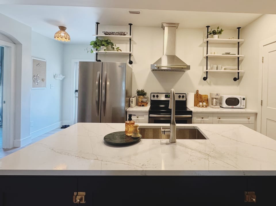 Bright modern kitchen with large island, stainless appliances & stylish shelving