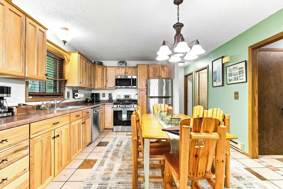Whip up your favorite recipes in a spacious, rustic kitchen complete with a modern gas stove, microwave, and dishwasher for easy cleanup. The adjoining wooden dining set offers the perfect setting for memorable group dinners.
