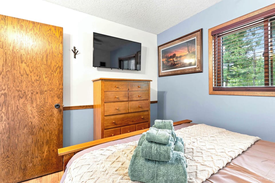 Wind down in comfort from the wooden bed, perfectly positioned for streaming your favorite shows on the wall-mounted flat-screen TV. Complete with a spacious wooden dresser for all your belongings and a view of the surrounding trees.