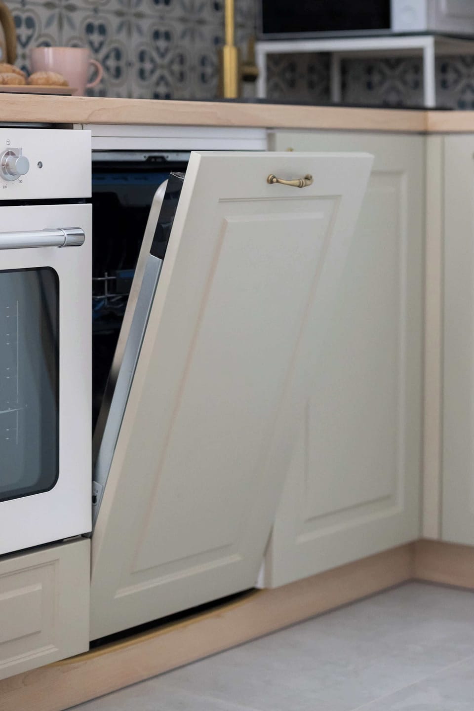 A close-up of the kitchen shows an oven, dishwasher, and beige cabinets. The wooden countertop adds warmth.