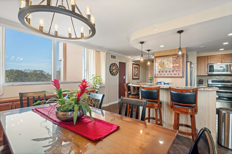 Sunlit open living with a dining table, breakfast bar, and natural treetop views—your perfect spot for morning coffee and evening meals.
